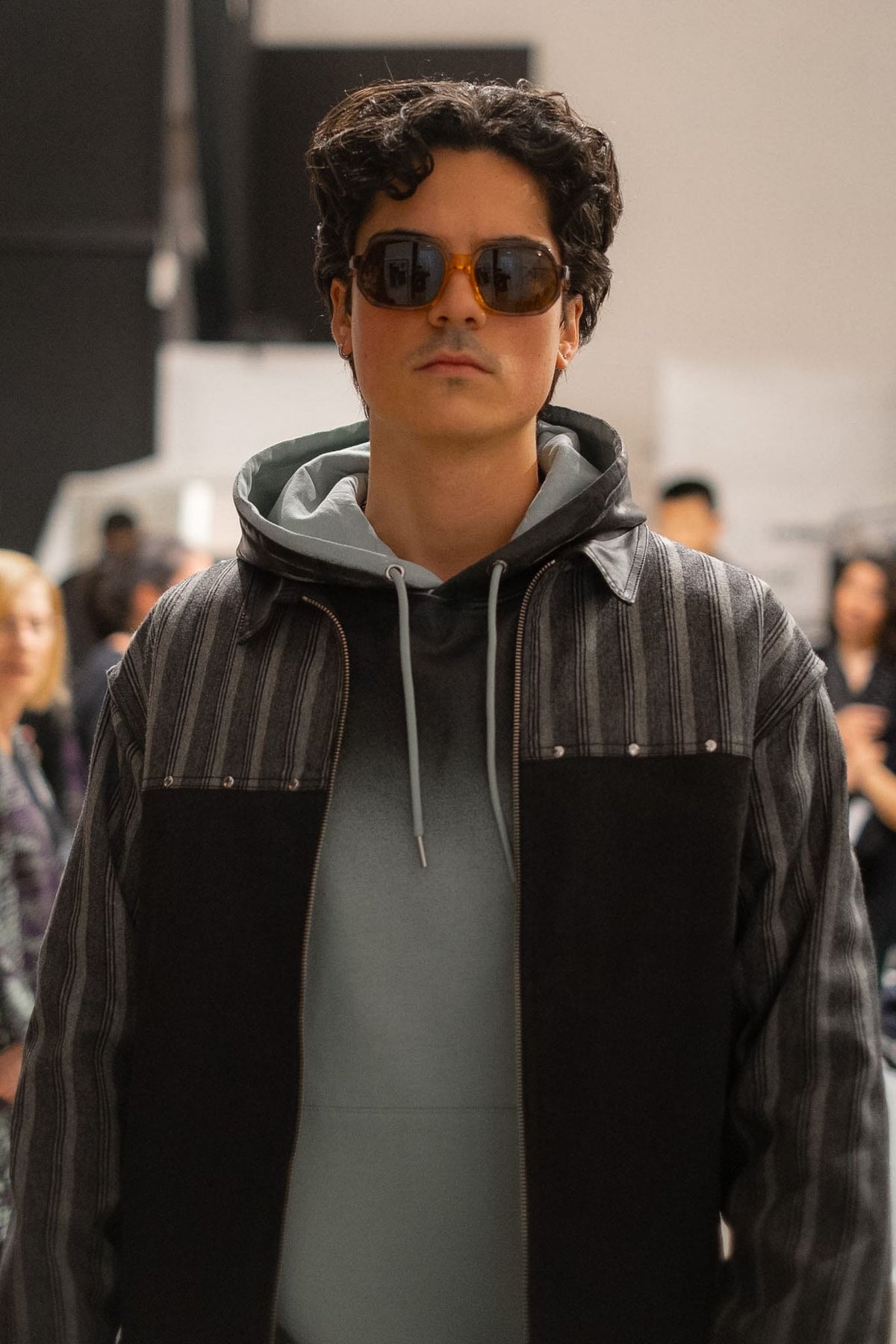 Close-up of the Smoked Green Sweater hood and drawstrings beneath a striped jacket